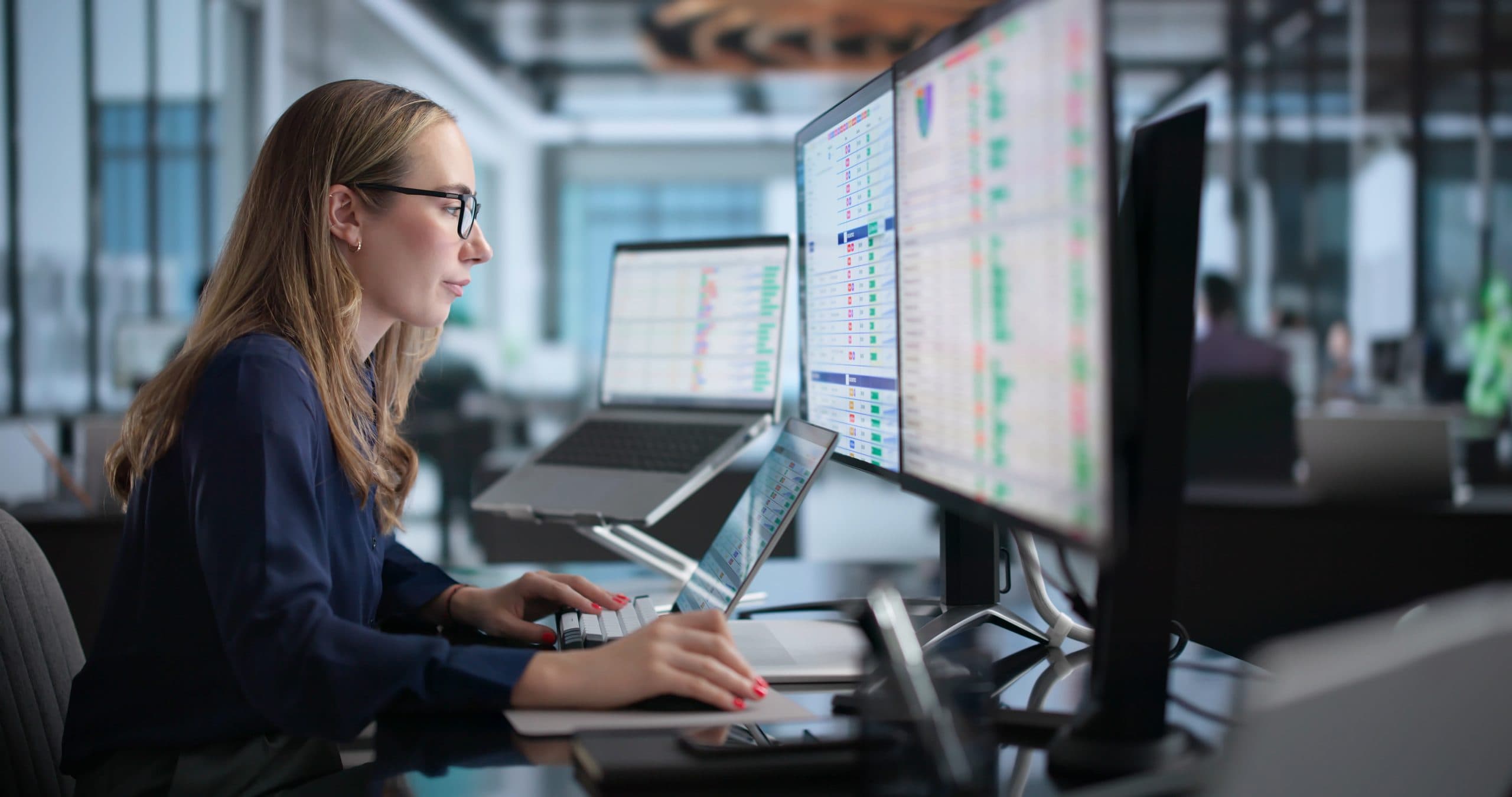 Professional analyzing operational data across multiple digital displays.
